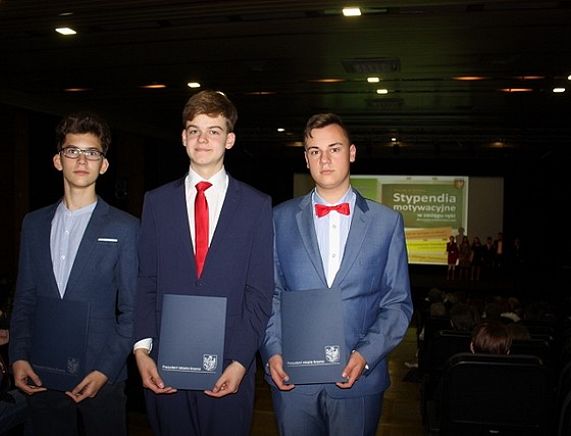 3 uczniów prezentujących dyplomy przyznające stypendium