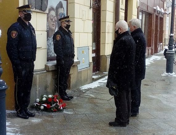 Obchody dni holokaustu w Krośnie. Na zdjęciu trzy osoby składanie wiązanki kwiatów i zniczy
