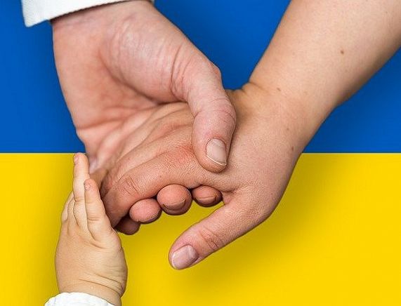 Splecione ręce na tle flagi ukraińskiej - fot. pixabay