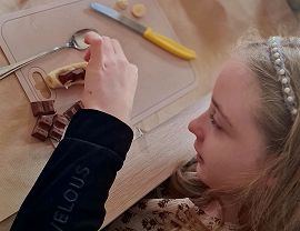 dziewczynka układa kostki czekolady na bananie