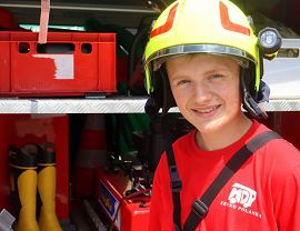 uśmiechnięty chłopiec w hełmie strażackim