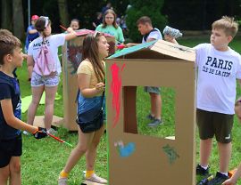 dzieci malują kolorowymi farbami duże kartonowe pudełka