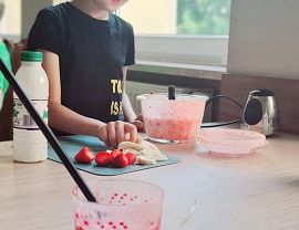 chłopiec przygotowuje truskawki na smoothie