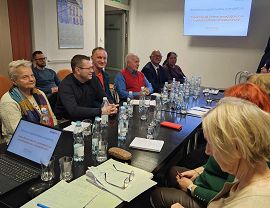 Osoby z organizacji pozarządowych rozmawiają przy stole na spotkaniu konsultacyjnym.