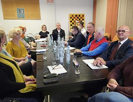 Osoby z organizacji pozarządowych rozmawiają przy stole na spotkaniu konsultacyjnym.